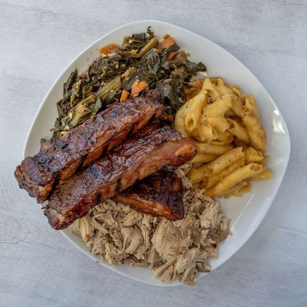 A plate of Warehouse BBQ ribs, pulled pork, collard greens, and macaroni and cheese.